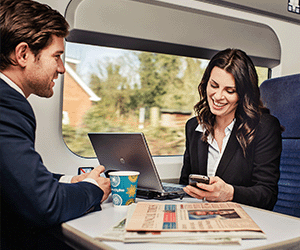 Business travellers on board a train on phones and laptop