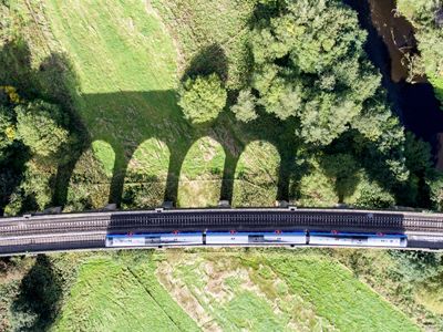 Train pictured from above going through green landscape